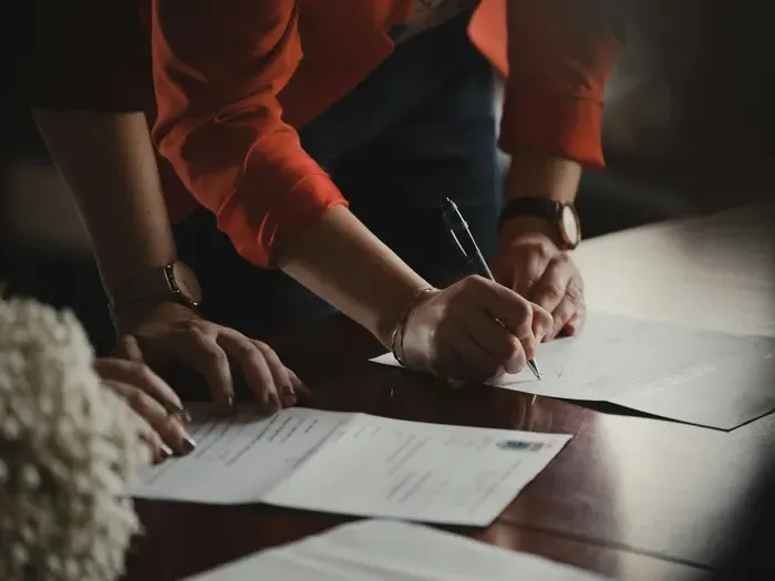 Person signing business documents, representing adding a listing and improving a company’s local visibility